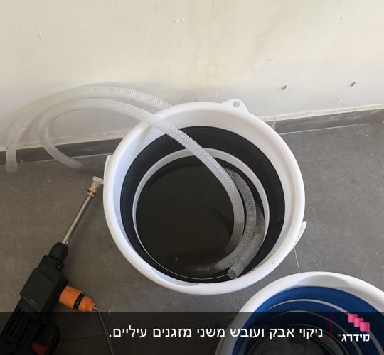 דלי עם צינור וכלי עבודה על הרצפה